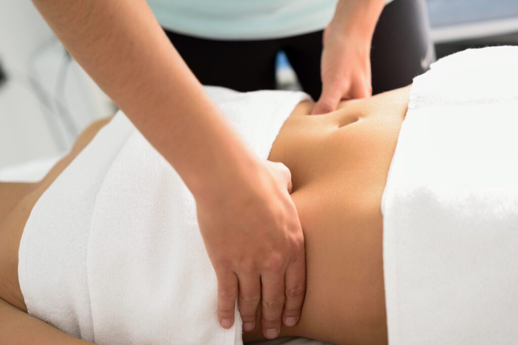 Mains du praticien posées sur l’abdomen d’une patiente pendant une séance de fasciathérapie