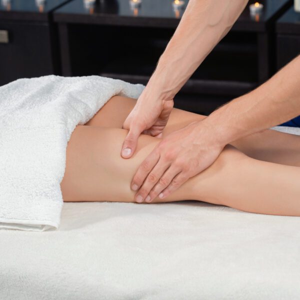 Mains du praticien massant délicatement le quadriceps pour stimuler la circulation lymphatique