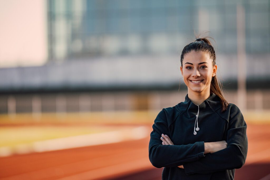 Portrait d’une jeune sportive souriante sur une piste d’athlétisme