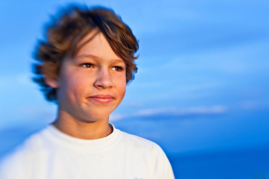 Portrait d’un garçon à la plage, regard tourné vers l’horizon