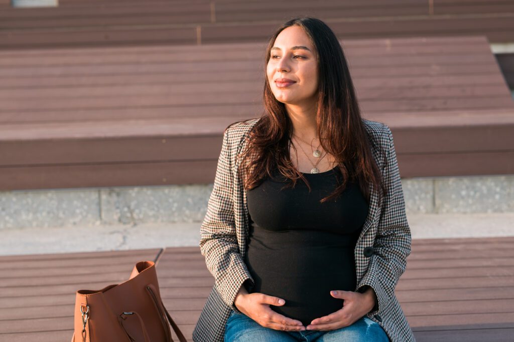 Femme enceinte assise, les mains sur son ventre, détendue